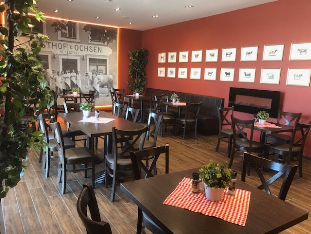 Ein gemütliches Restaurant mit Holzboden, roten Wänden und Tischdekorationen mit rot-weißem Muster.