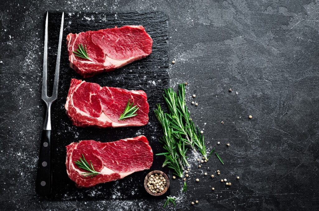 Raw meat, beef steak on black background, top view